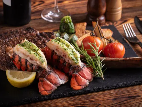surf and turf photo of two lobster tails and filet mignon.