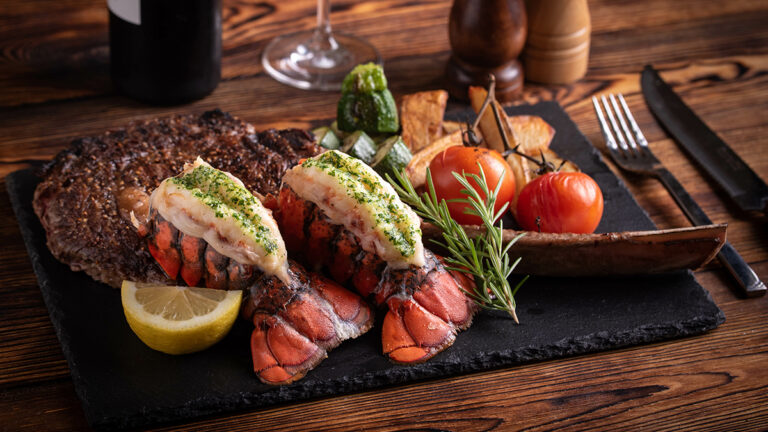 surf and turf photo of two lobster tails and filet mignon.