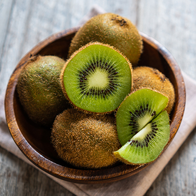 Fresh kiwi fruit in the bowl on wooden background