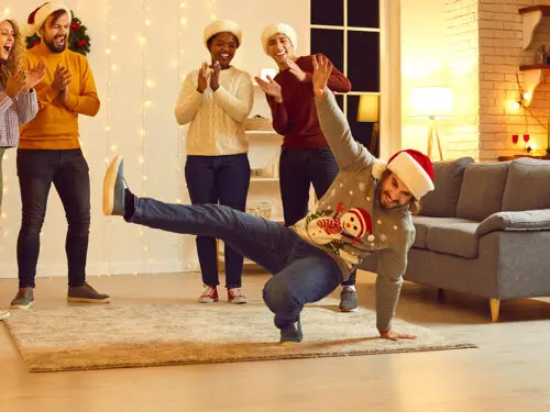 Group of happy young diverse people dancing and having fun at Christmas party at home