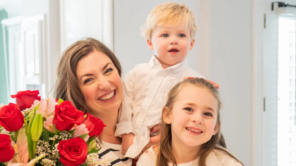 Jen Naye Herrmann with son and daughter and a bouquet of flowers.