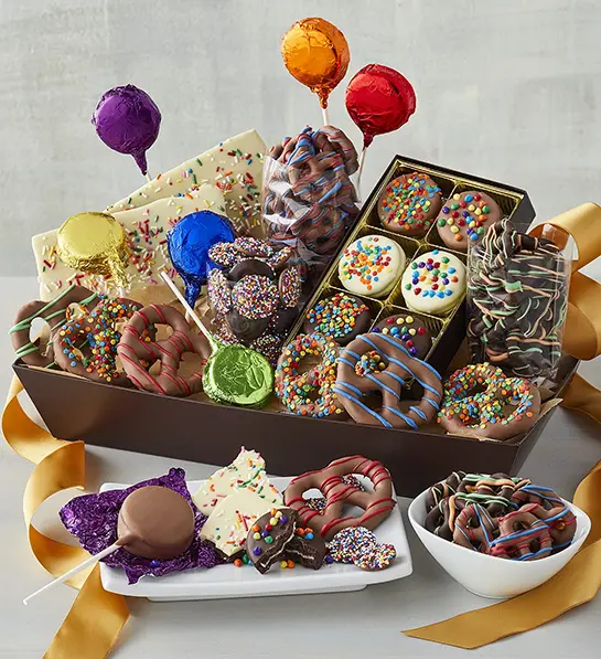 Box of chocolate covered pretzels, truffles, and other treats with mini balloons.