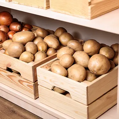 Crates with potatoes and onions on shelf. Orderly storage