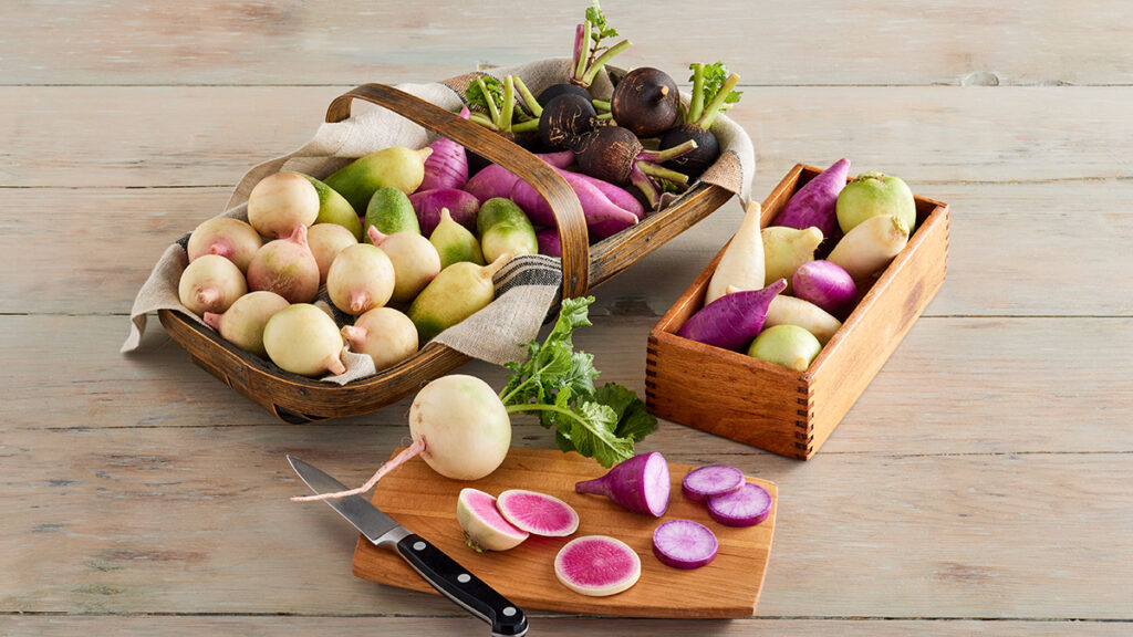 Types of radishes in a basket and a box, sliced and whole.