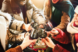 Group of friends trying winter wine pairings and raising glasses.