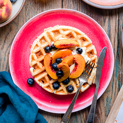 Breakfast for dinner with a plate of waffles topped with fruit.
