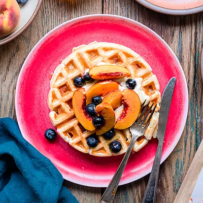 Breakfast for dinner with a plate of waffles topped with fruit.