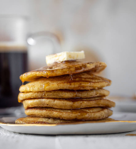 Dinner party ideas with a stack of pancakes topped with butter and syrup.