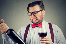 Man tasting wine and looking at bottle