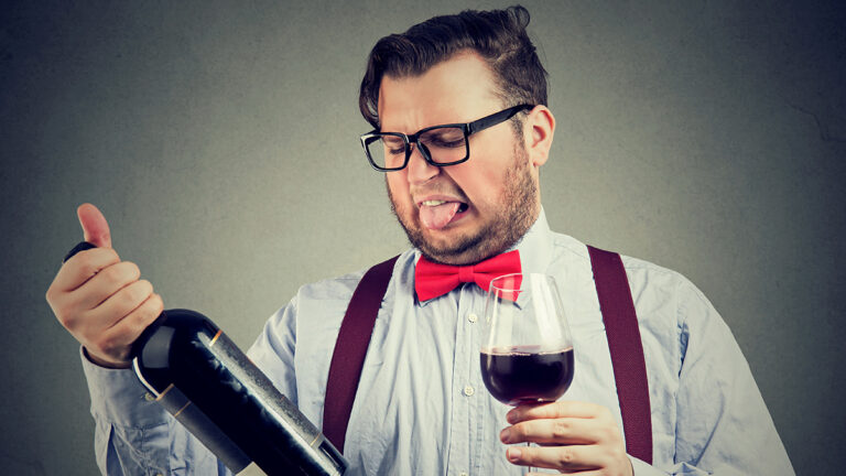 Man tasting wine and looking at bottle