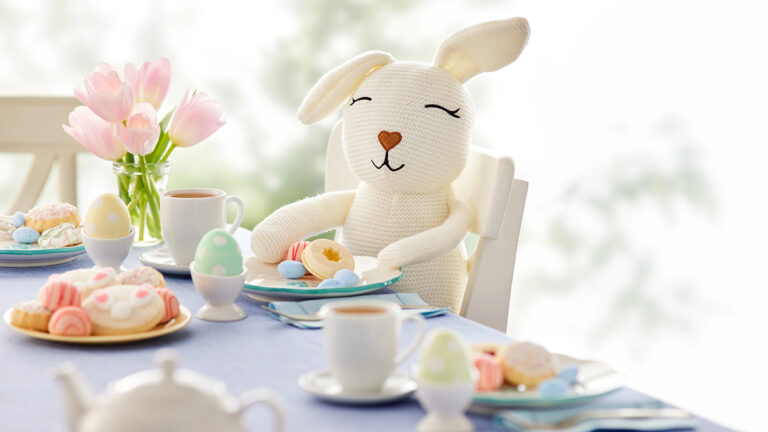 Easter decor ideas with a stuffed bunny sitting at an Easter table.