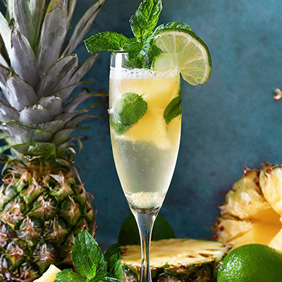 Pineapple recipes with a cocktail with pineapple and lime on a table.