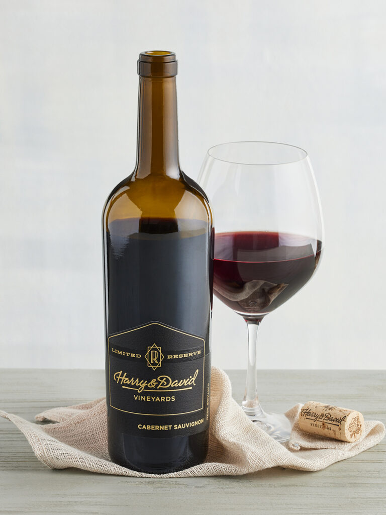 Bottle of reserve wine next to a glass of wine.