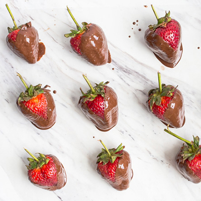 Rows of chocolate-covered strawberries on a marble counter.