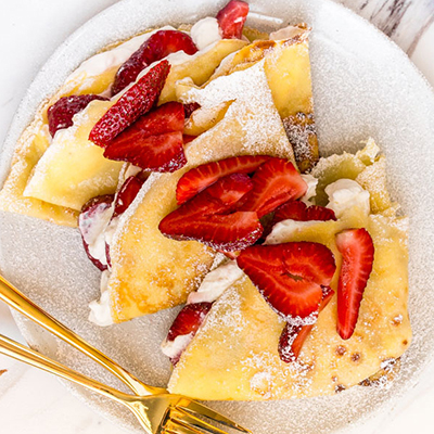 Strawberry recipes with a plate of crepes topped with strawberry.