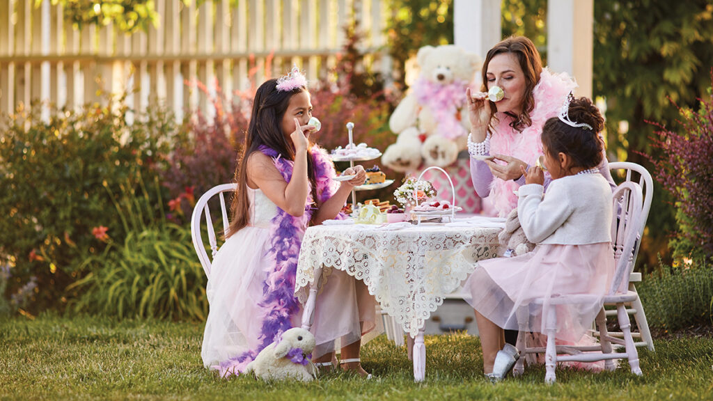 Girls and mom having a tea party outside.