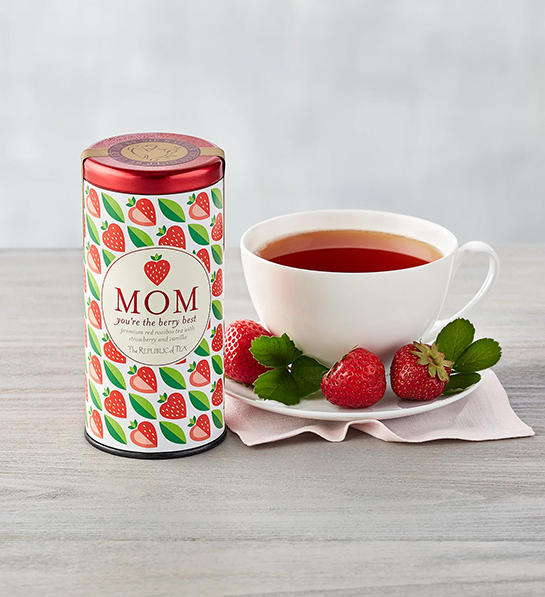 Strawberry tea tin next to a cup of tea for a tea party.